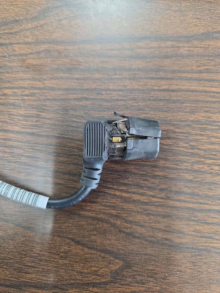 Metal electrical outlet adapter with white coiled cord on wooden surface